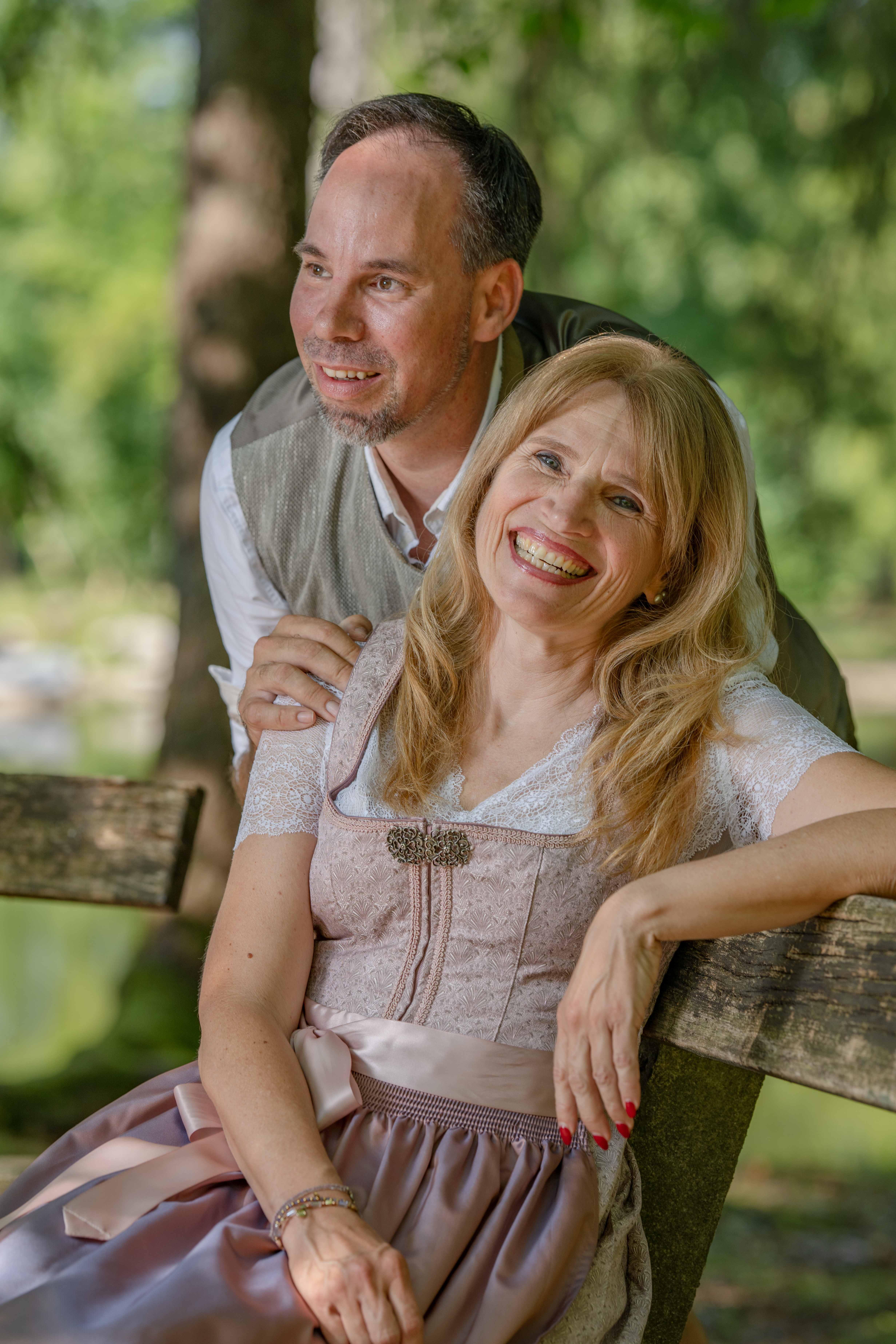 Fröhliches Paarporträt von Petra und Markus auf einer Holzbank