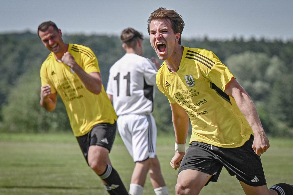 Zwei Fußballspieler in gelben Trikots jubeln auf dem Spielfeld