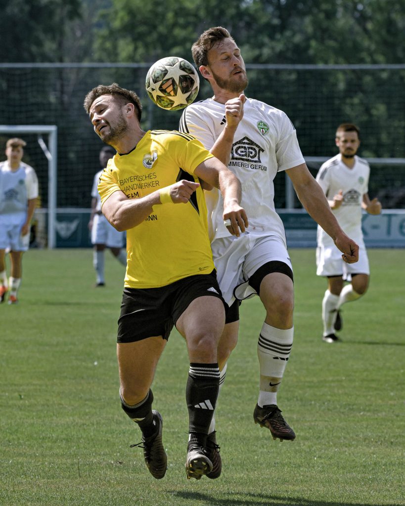 Zwei Fußballspieler in Gelb und Weiß springen zu einem Kopfballduell