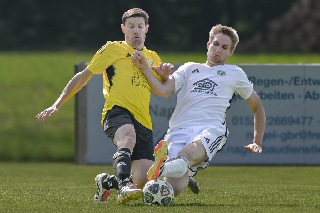 Fußballspieler in gelbem und weißem Trikot kämpfen am Boden um den Ball